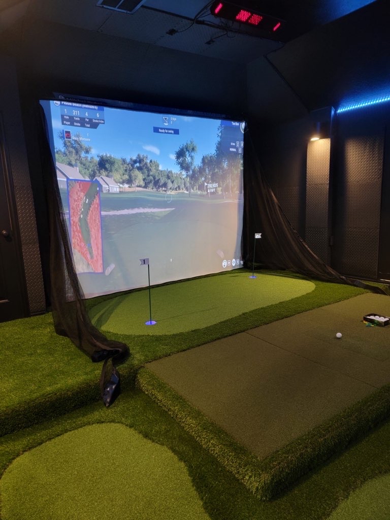 Custom home golf simulator room with a putting green