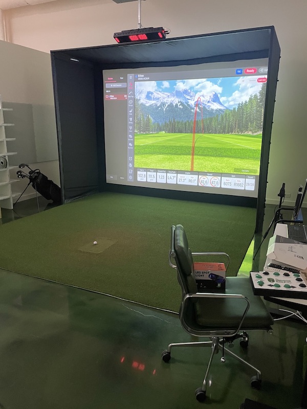 Golfer swinging in an indoor simulator bay